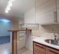 Kétszobás lakás konyhája fa dekor padlóval és bárpulttal.