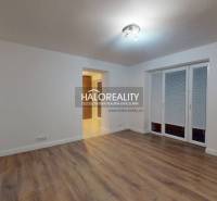 Nappali egy kétszobás lakásban fa dekor padlóval és francia ablakkal.