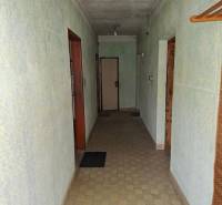 Egy családi ház folyosója világoszöld falakkal, csempével és egyszerű világítással.