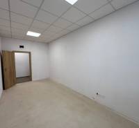 Iroda belső tér fehér falakkal, álmennyezettel és nyitott ajtókkal.