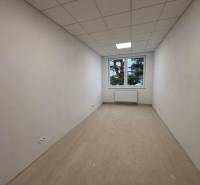 Fehér szoba ablakkal, radiátorral és fa dekorációjú padlóval az irodákban.