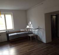 Családi ház fa mintázatú padlóval, ablakkal és bútorokkal.