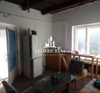 Egy szoba családi házban, világos asztallal az ablaknál, fotellel és étkezőasztallal.