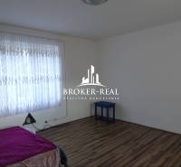 Szoba ággyal, függönyökkel és fa dekorációjú padlóval egy családi házban.