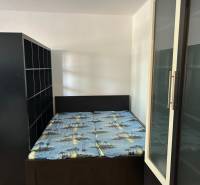 Hálószoba egy egyszobás lakásban ággyal és tárolószekrényekkel.