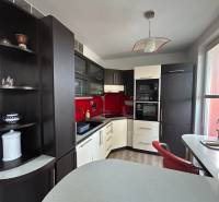 Konyha egy egyszobás lakásban fa mintázatú padlóval és piros csempével.