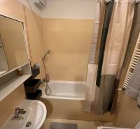 Fürdőszoba egy kétszobás lakásban káddal, mosdóval, mosógéppel és csempével.