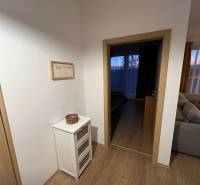 2 szobás lakás belső tere fa mintázatú padlóval, világos bútorokkal és dekorációkkal.