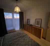 Hálószoba komóddal és lámpával, fa dekoros padlóval egy kétszobás lakásban.