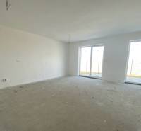 Tágas szoba egy családi házban betonpadlóval és nagy ablakokkal.