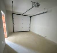 Fehér falú és elektromos kapuval ellátott garázs családi házban.