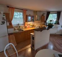 Konyha egy háromszobás lakásban fa dekor padlóval és étkezőasztallal.