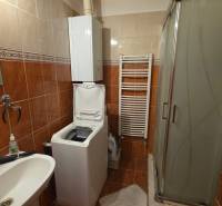 Fürdőszoba egy háromszobás lakásban mosógéppel, zuhanyzóval és kerámia burkolattal.