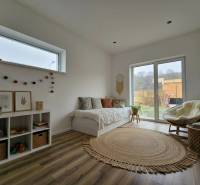 Világos szoba egy családi házban kanapéval, fa mintázatú padlóval és dekorációkkal.