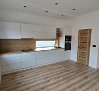 Konyha fehér szekrényekkel és fa dekorációval egy családi házban, fa dekorációjú padlóval.