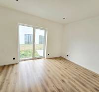 Családi ház belső tere fehér falakkal, fa mintázatú padlóval és nagy ablakkal.