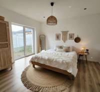 Hálószoba ággyal, kerek szőnyeggel, ruhásszekrénnyel és fa dekoros padlóval egy családi házban.