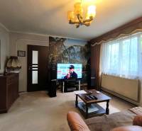 Nappali televízióval, kanapéval, asztallal és nagy ablakkal, családi ház.