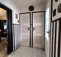 Családi ház belső tere fehér ajtókkal, csempével és sötét falburkolattal.