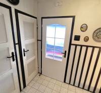 Családi ház belső tere fehér ajtókkal, faldekorációkkal és padlólapokkal.