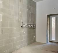 Világos szoba befejezetlen falakkal egy családi házban, bejárati ajtóval.