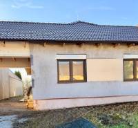 Családi ház Cíferen vakolatlan homlokzattal és barna tetőfedéssel.