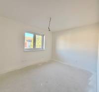 Tágas, világos szoba egy családi házban, dupla ablakkal és fehér falakkal.