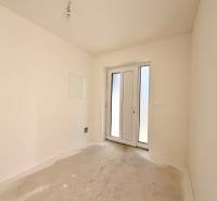 Üres szoba franciaajtókkal egy családi házban, fehér falak, betonpadló.