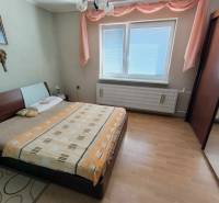 Hálószoba családi házban ággyal, szekrénnyel és fa dekoros padlóval.