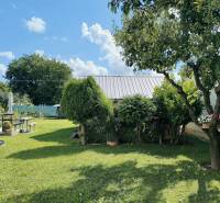 Családi ház kertje Partizánskén, gondozott gyep, fákkal és pihenősarokkal.