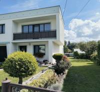 Családi ház Partizánskén, kerttel körülvéve, fákkal és zöld gyepes területtel.