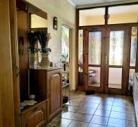 Családi ház folyosója tükörrel, dekorációkkal és üvegezett ajtókkal.