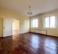 Tágas szoba fa mintás padlóval és két nagy ablakkal.