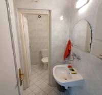 Iroda fürdőszobája tükörrel, mosdóval és WC-vel fehér csempéken.