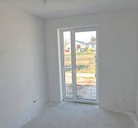 Fehér szoba egy családi házban nagy ablakkal és kilátással a kertre.