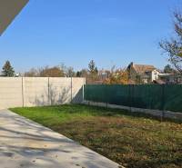 Családi ház kertje Pöstyénben gyepfelülettel, beton terasszal és kerítéssel.