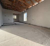 Családi ház belső tere betonpadlóval, fa gerendákkal és elektromos vezetékekkel.