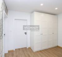 Fehér szekrény fa mintás padlóval egy kétszobás lakásban, finom mintás fal.