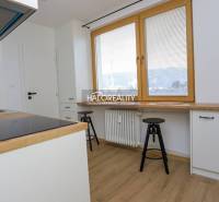 Konyha egy kétszobás lakásban fehér szekrényekkel és fa mintázatú padlóval.