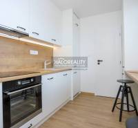 Két szobás lakás konyhája, fa mintázatú padló, világos helyiség nagy ablakkal.