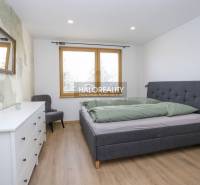 Hálószoba egy kétszobás lakásban ággyal, komóddal, tükörrel és fa mintázatú padlóval.