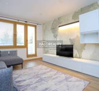 Világos nappali egy kétszobás lakásban kényelmes kanapéval és fa mintázatú padlóval.