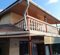 Ház Byštén terasszal és fa dekorációjú erkéllyel.