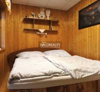 Hálószoba a faháznál fa fallal és polcokkal az ágy felett.