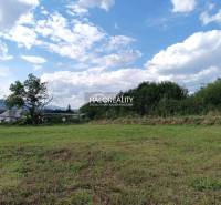 Telkek - lakóövezet Cserhóban, füves terület, fák, távoli házak, dombok, kék ég.