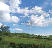 Telkek - lakóhelyek Csarhón, zöld rétek és kék ég felhőkkel.