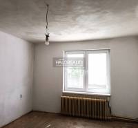 Üres szoba egy családi házban fehér falakkal, radiátorral és ablakkal.