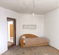 Családi ház belső tere régi kanapéval és nyers betonpadlóval.