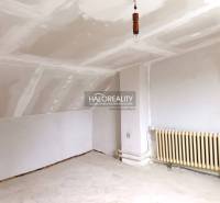 Belső tér fehér mennyezettel, radiátorral és padlóval egy családi házban.