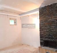 Családi ház belső tere kő kandallóval és kis ablakkal.